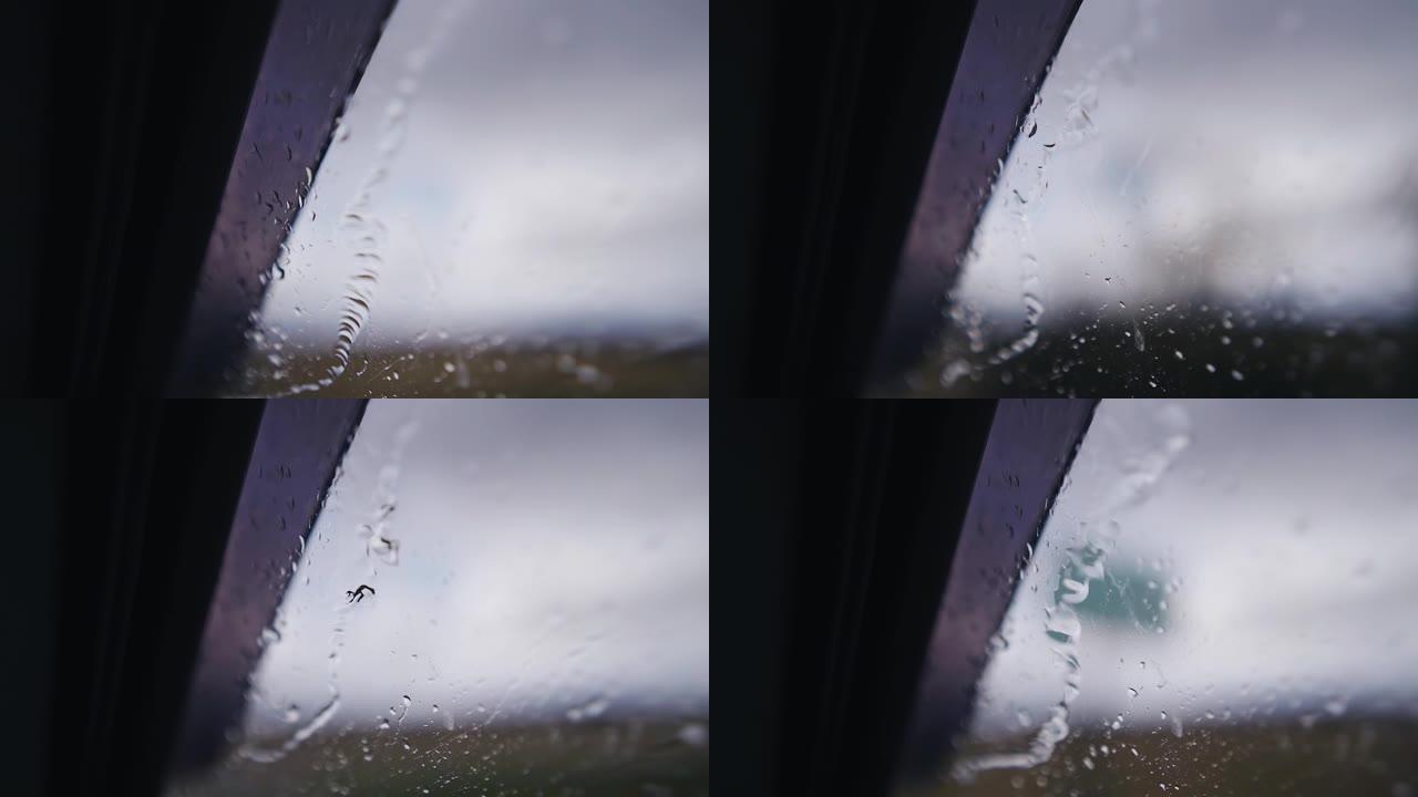 在雨中行驶时，水滴沿着车窗向下流过。特写拍摄