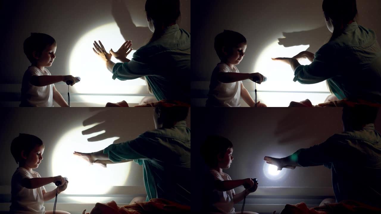 4k的视频，年轻的母亲用手和手电筒在卧室的墙壁上显示动物的阴影，然后与蹒跚学步的儿子一起睡觉