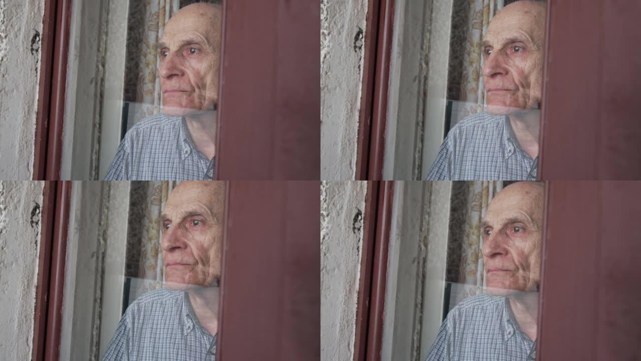 悲伤的老人站在门玻璃后面，透过窗户看。