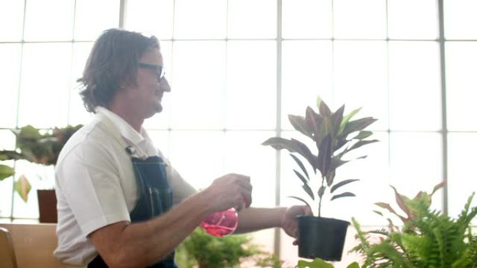 快乐的老人在业余花店给他的植物浇水