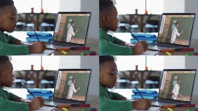 非裔美国男孩在家里用笔记本电脑与男老师进行视频通话时做作业