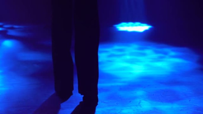 时尚性感女人的剪影阿根廷弗拉门戈舞元素在黑暗的烟熏工作室在蓝光。穿着长裤套装和帽子的西班牙舞者在舞蹈