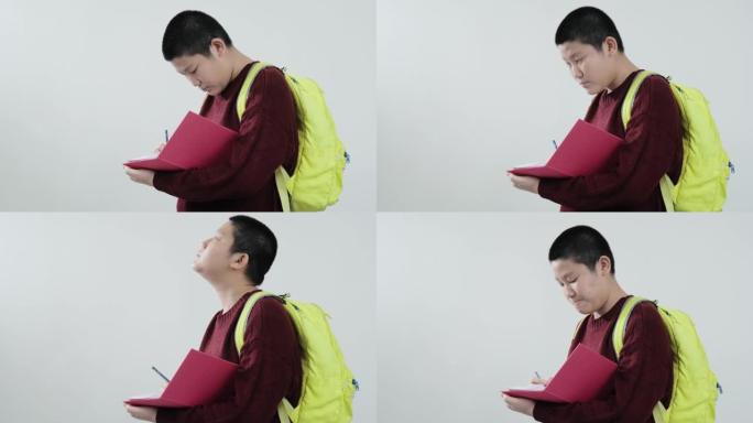快乐的亚洲男生穿着红色毛衣在灰色背景，生活方式概念上的粉红色书讲座。