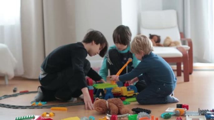 可爱的孩子，兄弟们，玩五颜六色的玩具积木。小男孩在阳光明媚的宽敞卧室的地板上建造积木玩具的房子。儿童