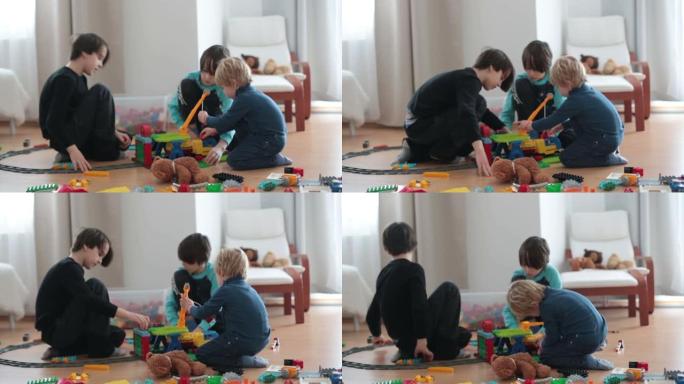 可爱的孩子，兄弟们，玩五颜六色的玩具积木。小男孩在阳光明媚的宽敞卧室的地板上建造积木玩具的房子。儿童