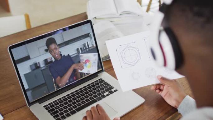非裔美国男大学生在家里用笔记本电脑进行视频通话时拿着笔记