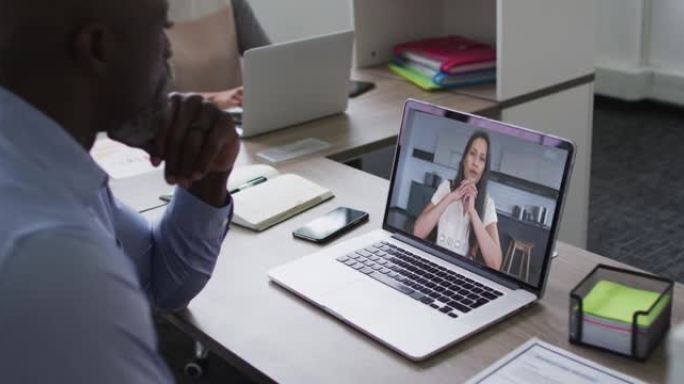 非裔美国高级男子在笔记本电脑上与办公室的女同事进行视频通话