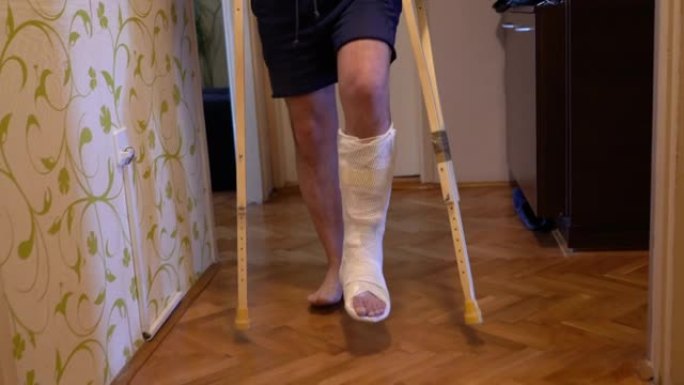 断腿的成熟男人在家里用拐杖走路