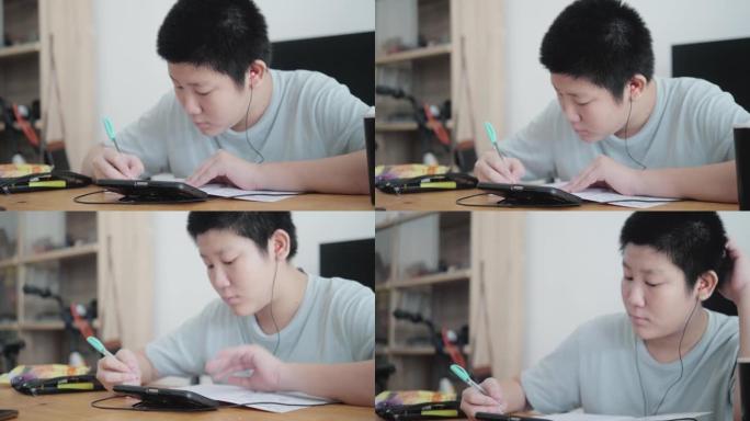 亚洲男孩在新型冠状病毒肺炎期间通过智能手机学习在线课程，检疫生活方式概念。