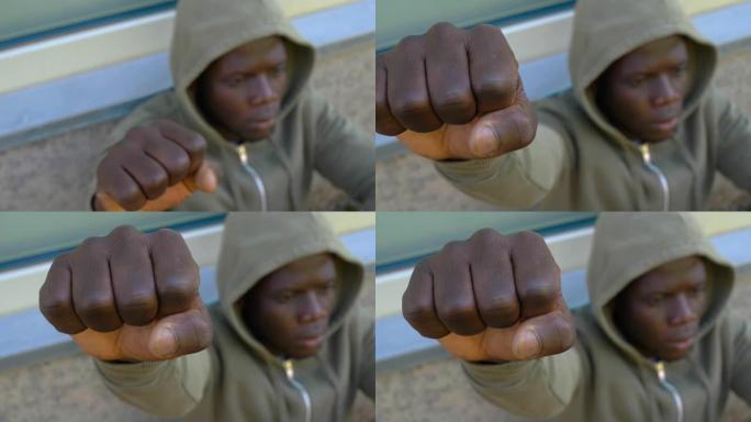 年轻的蒙面黑人男子举起他的拳头对着镜头-模糊