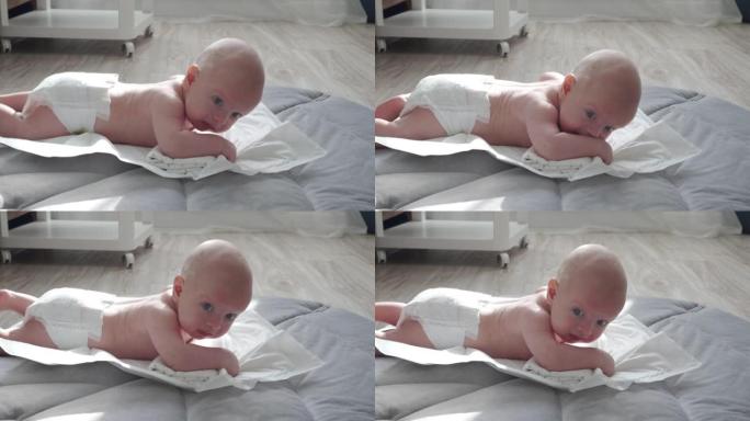 婴儿的肚子时间，婴儿学习头部控制，3个月大的男婴抬起头躺在肚子上活动在家里玩垫子。