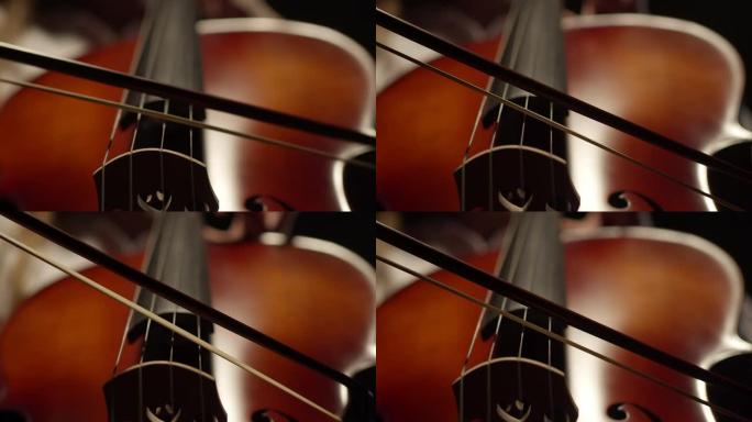 弓在黑暗的背景下在大提琴弦上缓慢演奏。轻触弓弦木器。概念艺术
