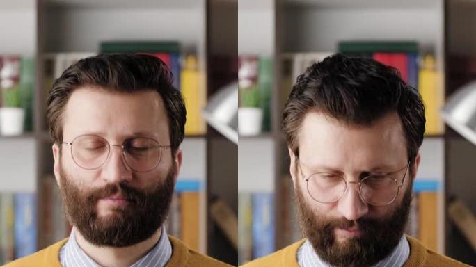 男人点头表示同意。垂直视频的正面胡子男子戴眼镜在办公室或公寓房间看着摄像头，并积极点头，信号是或你好