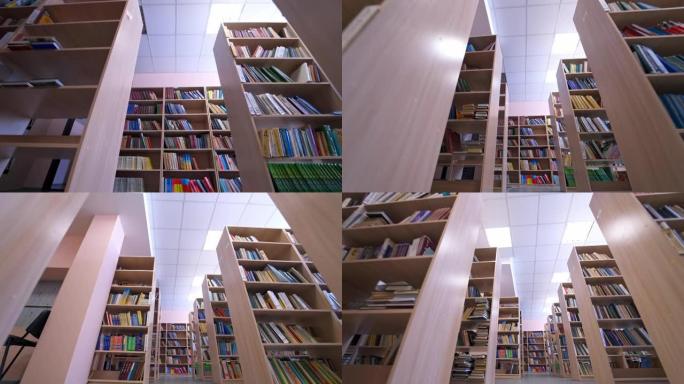 图书馆书籍堆放在书架上。图书馆里一排排藏书的书柜。教育、学校或大学学习概念。摄像机向后移动。