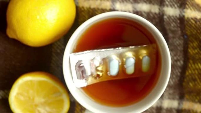 药丸掉进一杯柠檬茶中，特写。秋寒，病