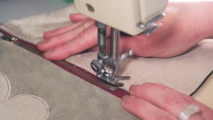 熟练的高加索专业女裁缝用缝纫机将拉链固定在皮革上