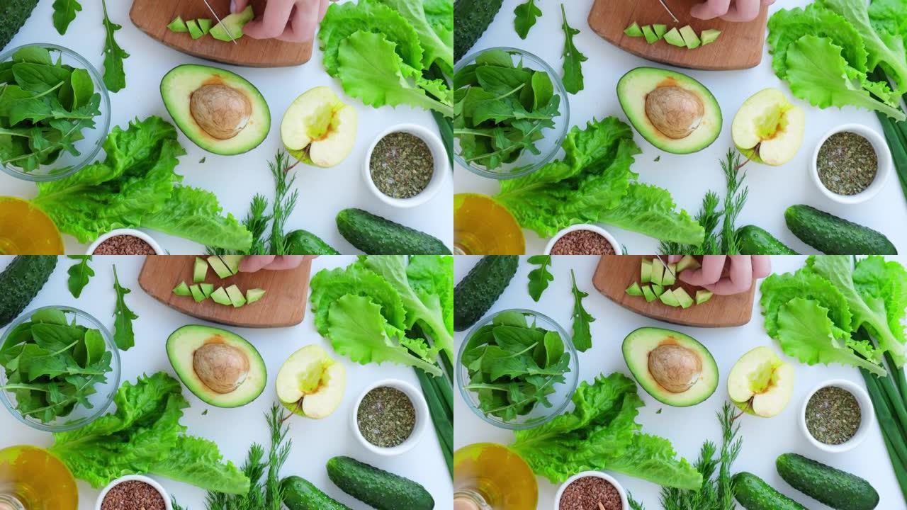 女人烹饪新鲜绿色蔬菜和香草沙拉。生食概念。素食菜单。烹饪健康饮食或素食。女性的手将鳄梨切成绿色蔬菜包