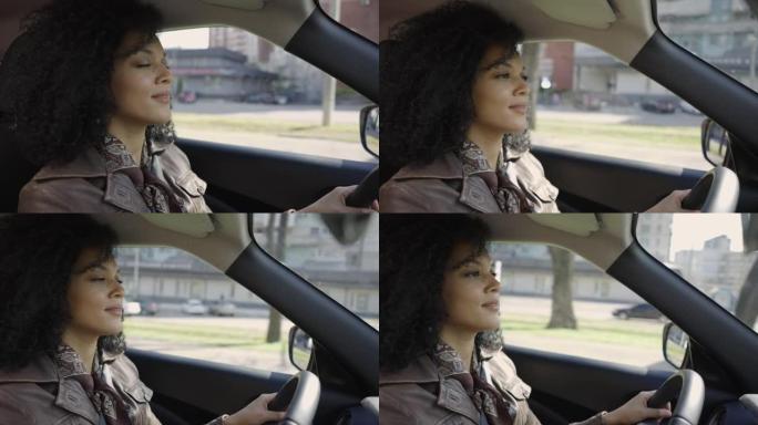 一位时尚的年轻非洲裔美国妇女驾驶汽车的肖像。穿着棕色皮夹克的黑发黑发在汽车的方向盘后面摆姿势。特写。