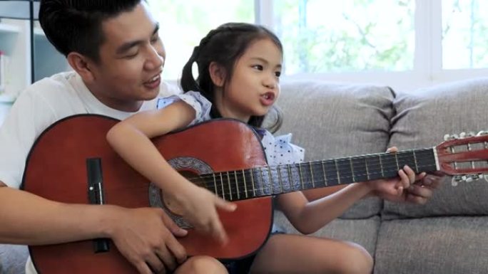 亚洲父亲教女儿在家弹吉他