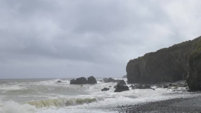 有岩石和悬崖的海滩。猛烈的海浪和多云的天空。库珀海岸，沃特福德。爱尔兰