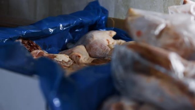 一副用过的手套被扔在装有冷冻鸡腿的盒子上的特写镜头。鸡肉的包装和冷冻过程，供在家中进一步使用。4k视