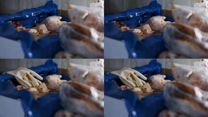 一副用过的手套被扔在装有冷冻鸡腿的盒子上的特写镜头。鸡肉的包装和冷冻过程，供在家中进一步使用。4k视