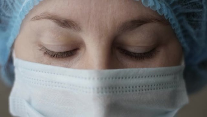 悲伤的病人，过度劳累的严肃的女医护人员看着镜头沮丧。肖像特写医生护士戴着防护面具，防止传染性电晕病毒