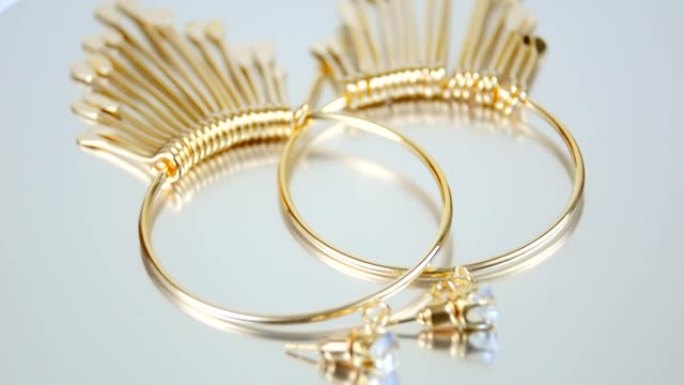 白色背景上的金色耳环，圆形，白色背景上的奢华昂贵的珠宝