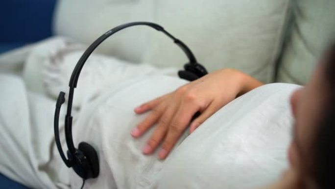 亚洲孕妇戴着耳机给未出生的婴儿播放音乐