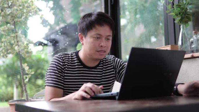 亚洲人坐在咖啡店里用笔记本电脑工作。