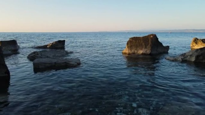 在海岸线上岩石之间的水面上空低空飞行