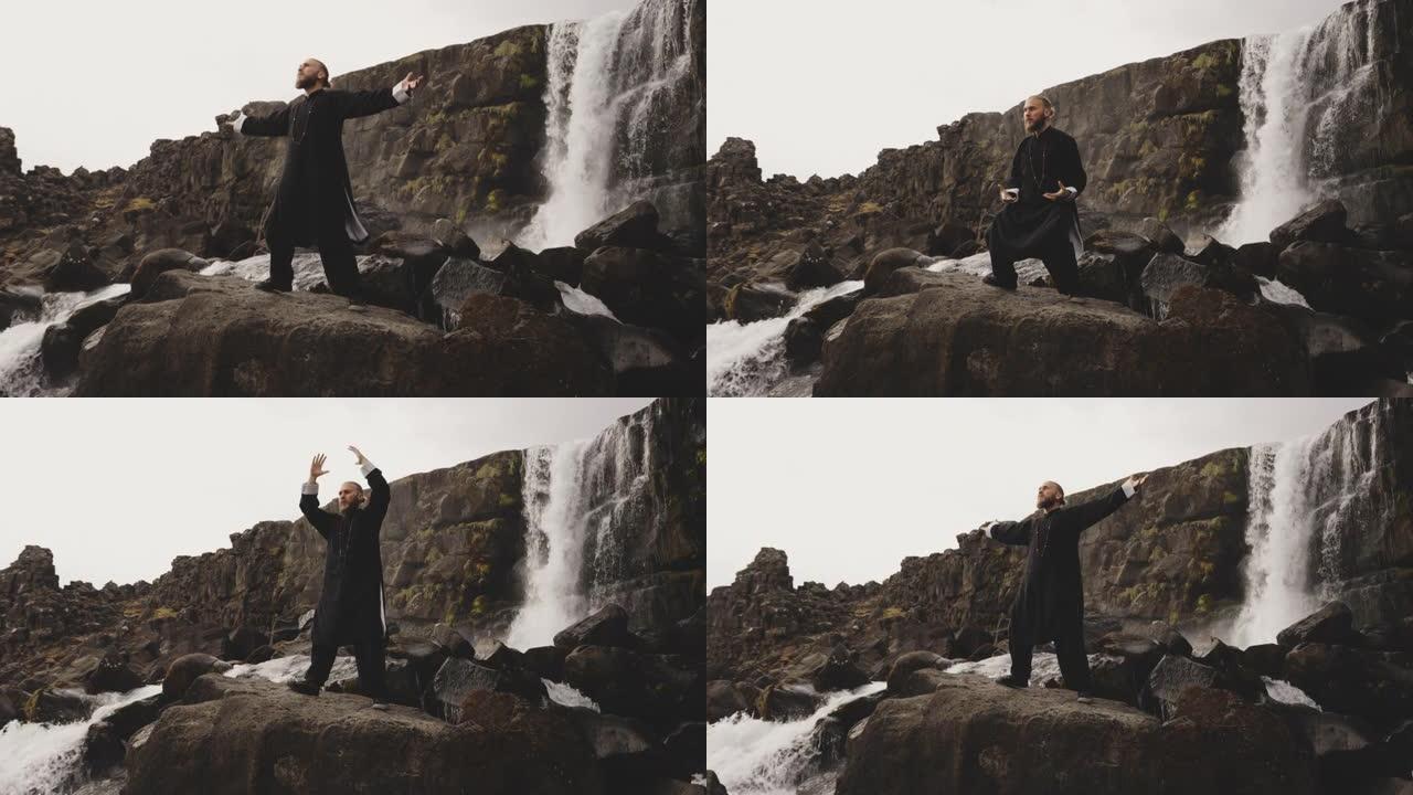 功夫大师在瀑布上的岩石上表演武术