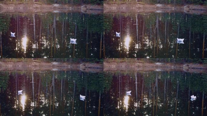 纸船在夕阳的光线中和平地在水面上航行，冲破树木，并与针叶树一起在水中反射。折纸船