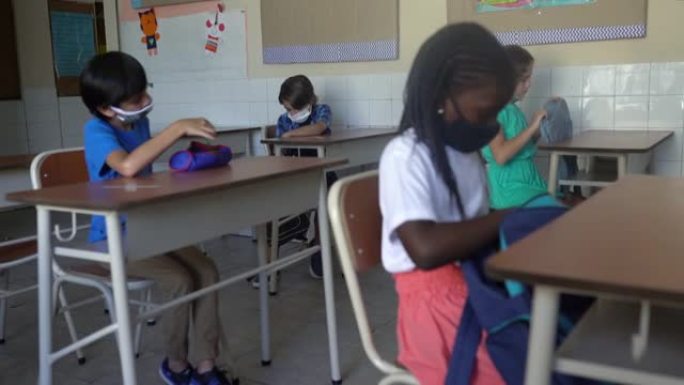 学生戴着口罩，在教室里从背包里拿出教材。新型冠状病毒肺炎概念