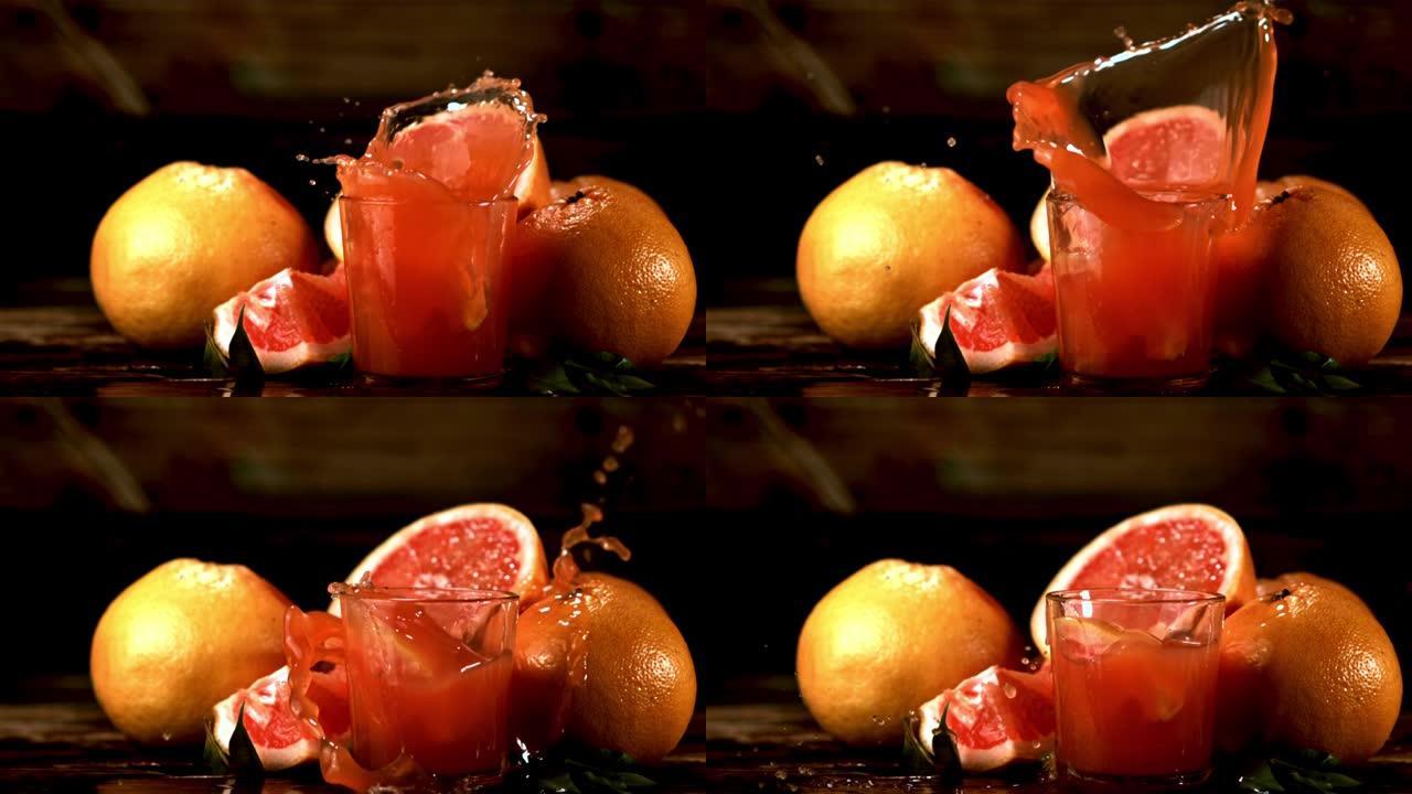 用葡萄柚汁在玻璃杯中超慢动作掉落一块带有喷雾的葡萄柚。以1000 fps拍摄。