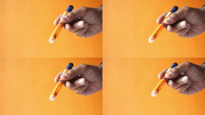 橙色背景下手持胰岛素笔