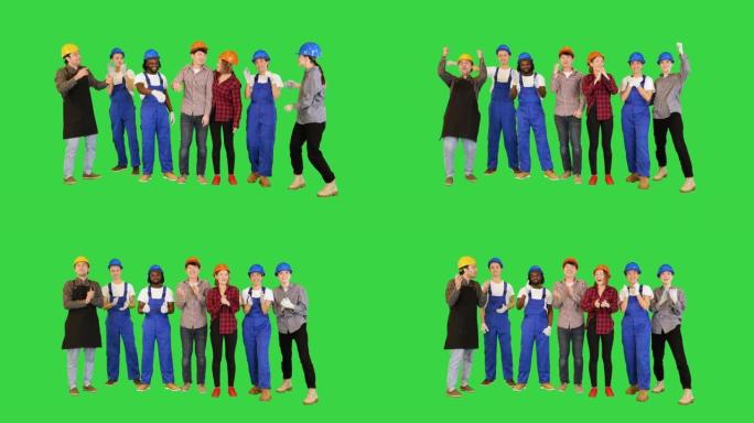 一群男女工程师和工人在绿色屏幕上完成任务或施工后举起手，色键