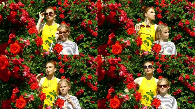 戴墨镜的女人和女孩在玫瑰背景下在花园里摆姿势