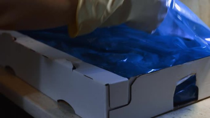手套打开装满冷冻鸡腿的盒子的手的特写视图。用冰覆盖的冷冻生鸡肉。4k视频