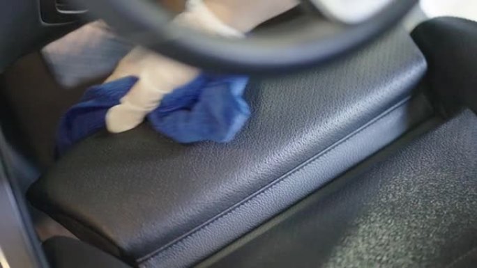 汽车细节工人用蓝色毛巾擦拭驾驶员座椅。