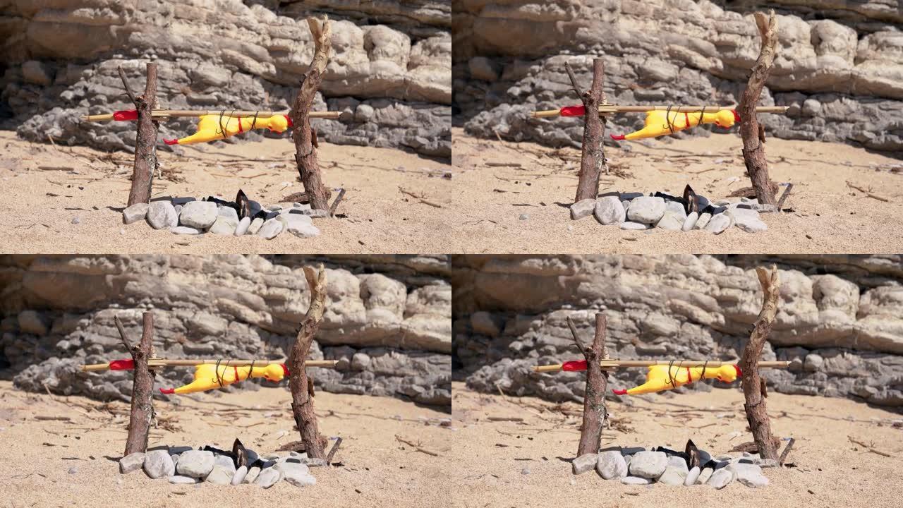 野生原住民准备篝火烤绑在自制唾沫上的玩具鸡。在荒岛上迷路的人。狩猎的概念。野餐，海滩上温暖的晴天