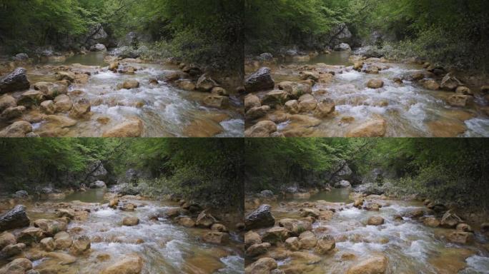 宁静的溪流在风景如画的野外岩石和巨石周围流动。高清视频