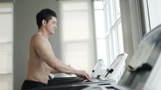 英俊的男人在健身房的跑步机上跑步。锻炼使你的身体强壮健康。运动员美丽的肌肉。通过运动来照顾你的健康。