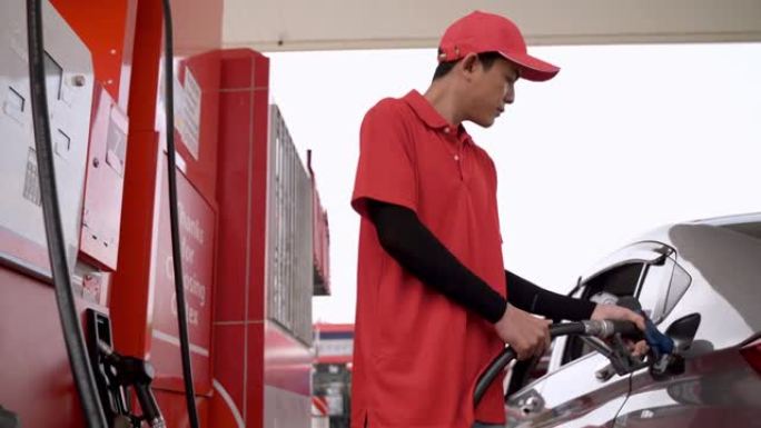 工人手持汽油在气泵处泵送燃油。男子在加油站给汽车加油。在加油站给汽车加油。将燃油泵入油箱。