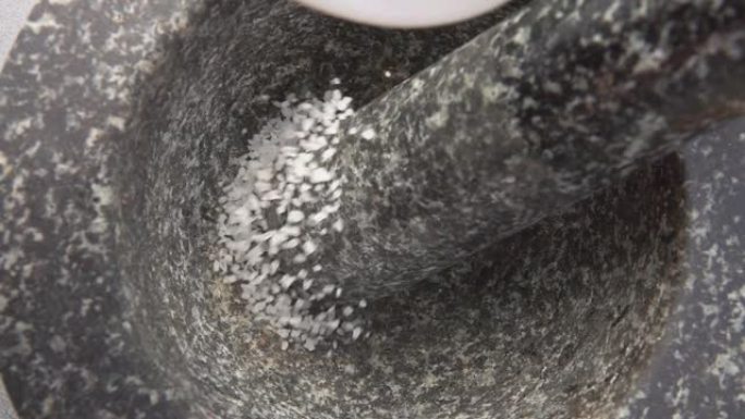一种白色海盐在慢动作中落入灰色石质砂浆的特写镜头