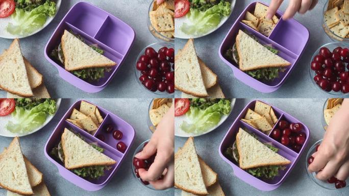 女人拿走，在午餐盒里放一个三明治。学校或办公室午餐，健康零食三明治，樱桃和饼干
