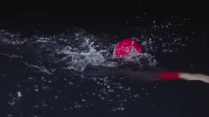 铁人三项运动员穿着潜水服在漆黑的夜晚游泳