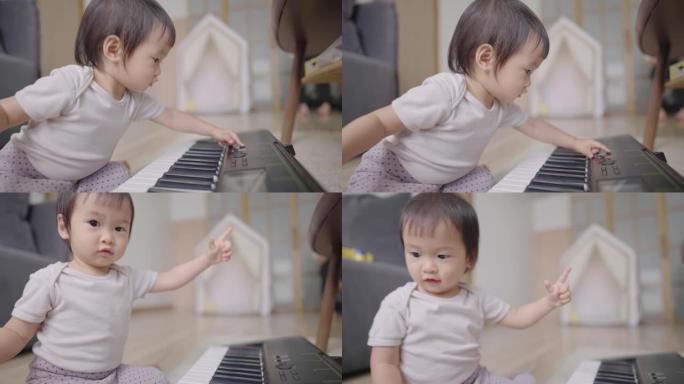 一个可爱的亚洲婴儿好奇地检查每个电子钢琴按钮的不同声音，一个顽皮的聪明的女婴坐在地板上，家里有教育乐
