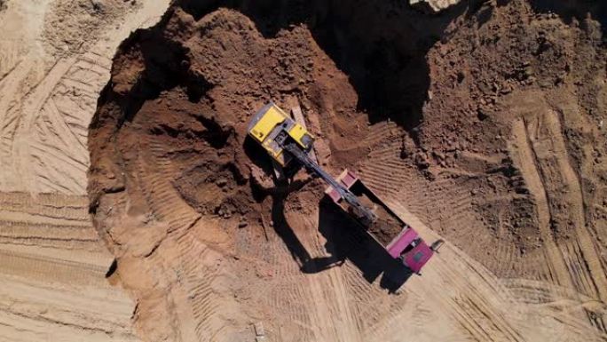 挖掘机的鸟瞰图将沙子装载到自卸车中。土方工程的后孔