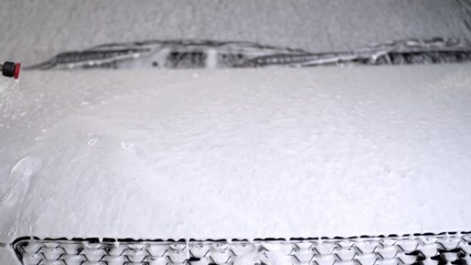 用于消失和清洁的白色泡沫在车辆的前车裙体周围流动。化学雪泡沫洗车概念清洁产品。